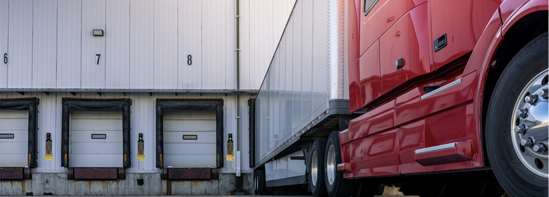 red semi truck pulling away from a loading dock