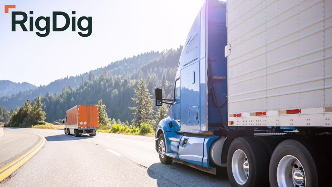 Blue semi-truck on a curved mountain highway with a white trailer, RigDig logo in the top-left corner.